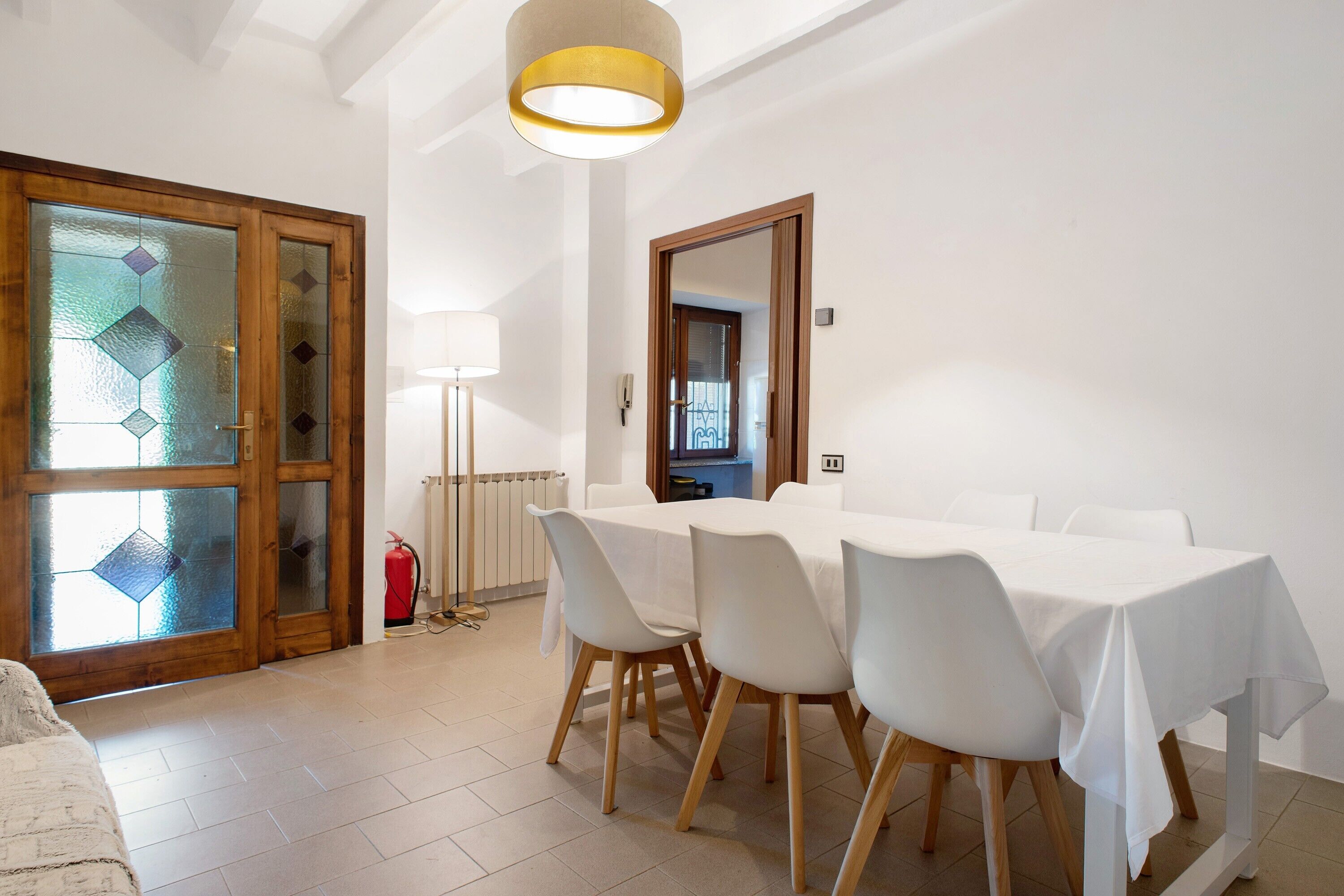A dining area with a table set for four, a fire extinguisher, and a mirror on the wall.