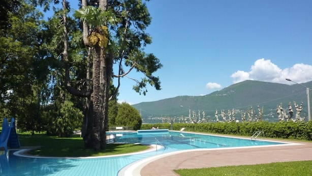 Ein Pool mit gewundener Wege, umgeben von Grün und Blick auf die Berge.