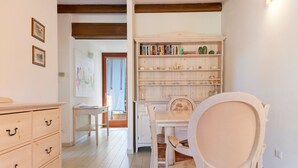 Ein Zimmer mit einem Holzkoffer, einem Schreibtisch mit Stuhl, einem Bücherregal und einer Tür zu einem anderen Raum.