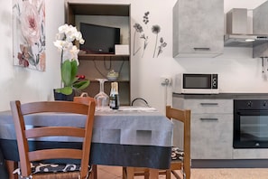 A modern kitchen with a built-in microwave, oven, and a dining area with a table and chairs.