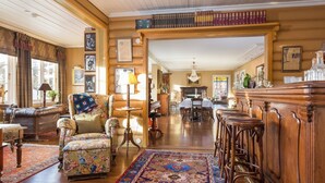 A spacious living room with a large wooden bar, a patterned rug, and a collection of books on a shelf. - Geilo Mountain Lodge (Geilo)