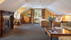 A cozy living room with a fireplace, a sofa, a coffee table, and a window with curtains. - Geilo Mountain Lodge (Geilo)