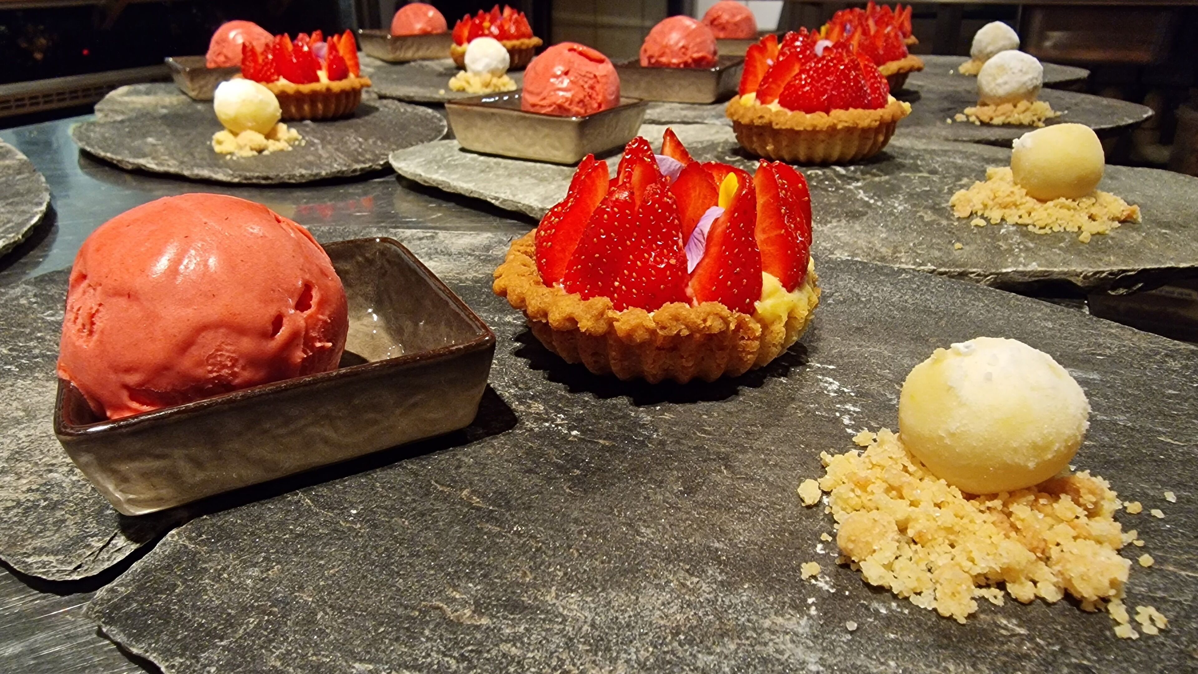 A dessert display with various ice cream flavors and toppings.