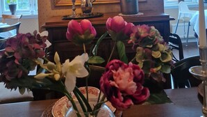 A dining area with a chandelier, a framed portrait, and a table with flowers. - Geilo Mountain Lodge (Geilo)