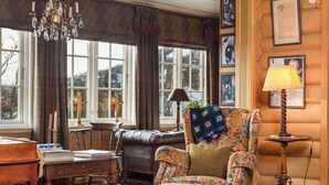A cozy room with a leather armchair, a wooden table with books, a lamp, and a chandelier. - Geilo Mountain Lodge (Geilo)