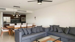 A modern living room with a sectional sofa, a glass coffee table, and a ceiling fan.