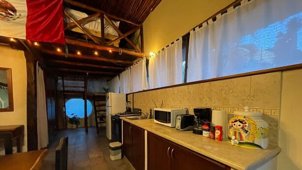 Une cuisine avec un plafond en bois, un four à micro-ondes, un grille-pain et un bocal décoratif posé sur le comptoir.