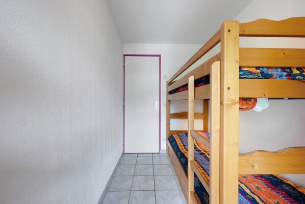 A room with a bunk bed, a door, and tiled flooring.