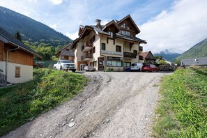 Un bâtiment à deux étages, avec un magasin de ski au rez-de-chaussée, une vue sur la montagne et une allée de gravier menant à l’entrée.