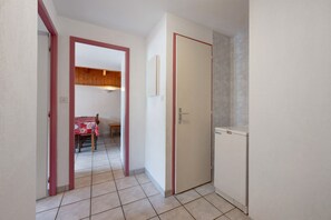 Un pasillo estrecho con una puerta que da a un comedor con mesa y sillas.