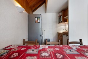 Une cuisine de taille réduite, équipée d’un réfrigérateur, d’un four à micro-ondes et de meubles de rangement en bois.