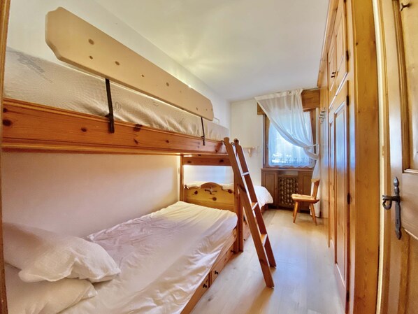 A bunk bed room with a ladder, wooden wardrobe, and a small table. - Cozy 3 bedroom in amazing location (Cortina d'Ampezzo)