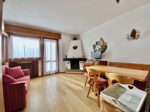 Un salon chaleureux avec une table à manger en bois, des chaises, un canapé et une cheminée.