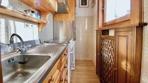 A compact kitchen with wooden cabinets, a stainless steel sink, and a built-in stove. - Cozy 3 bedroom in amazing location (Cortina d'Ampezzo)