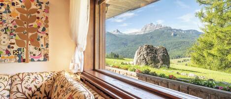A cozy room with a wooden bench and a large window offering a view of a mountain landscape.