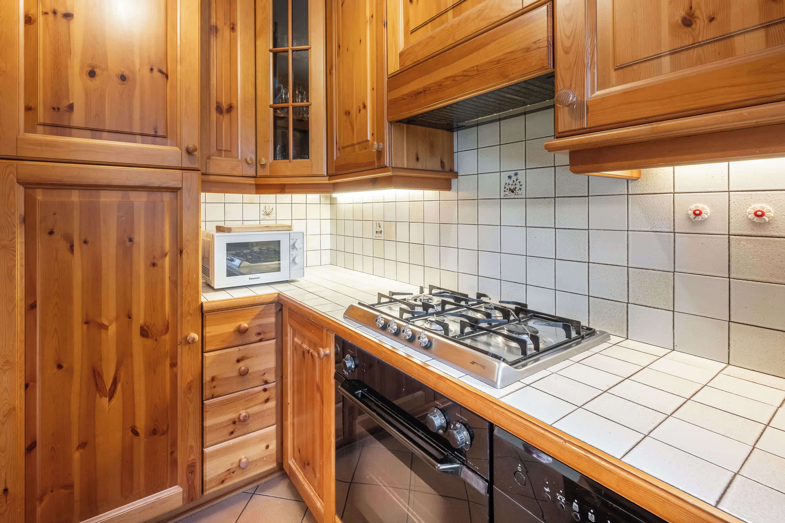A kitchen with wooden cabinets, a gas stove, and a microwave.