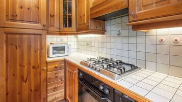 A kitchen with wooden cabinets, a gas stove, and a microwave.