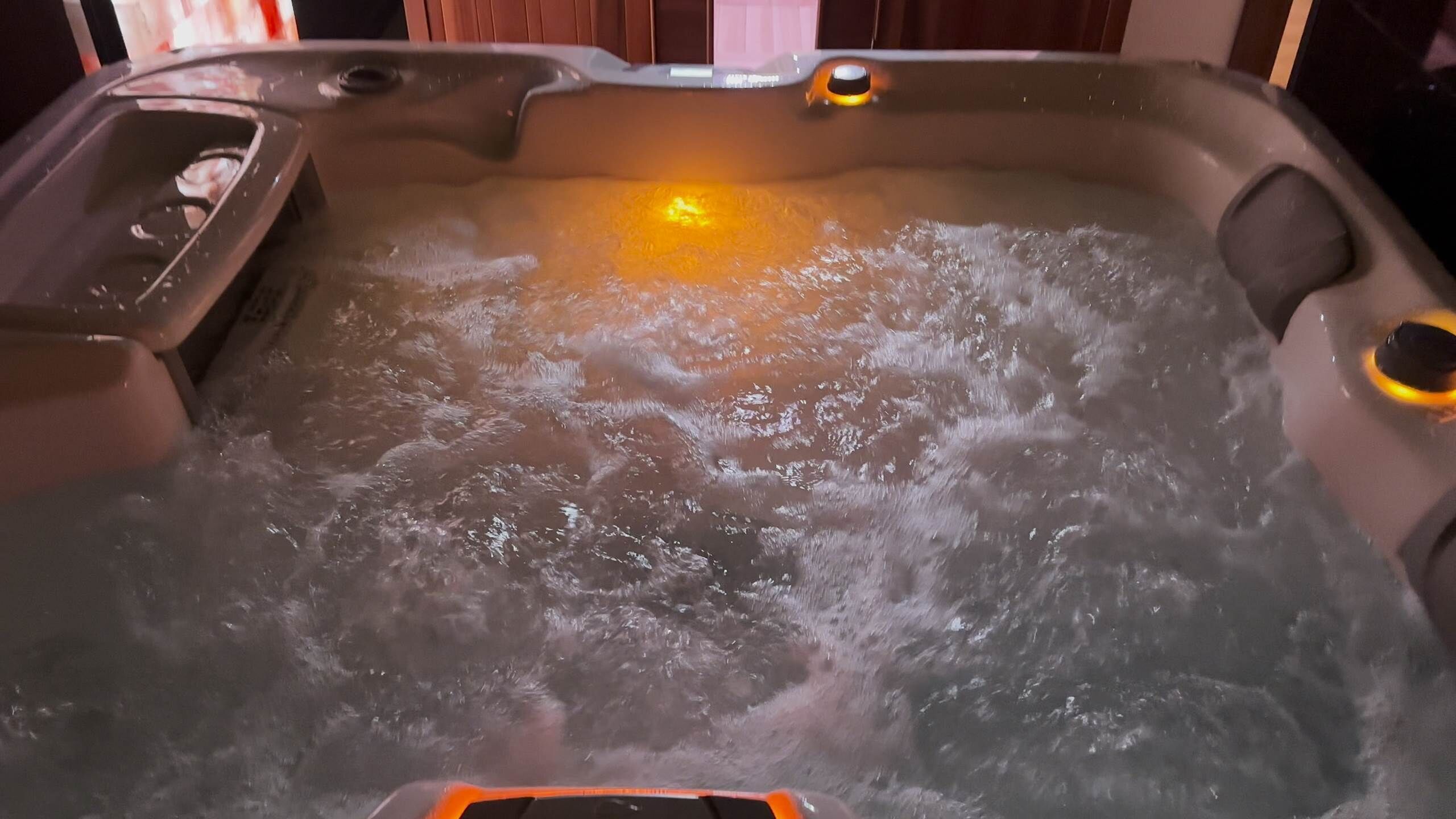 A hot tub with water jets, a control panel, and a light.