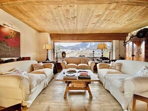 A cozy living room with two sofas, a wooden coffee table, and a view of a mountainous landscape through large windows. - Luxury flat with views - few steps from centre (Cortina d'Ampezzo)