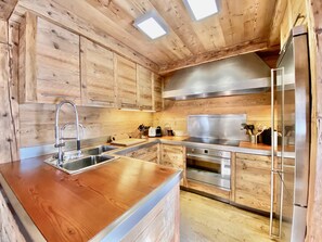 Eine moderne Küche mit Holzschränken, Edelstahlgeräten und einer Holzausziehtafel.