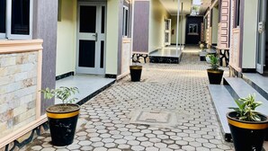 A corridor with hexagonal tiled flooring, potted plants, and doors leading to rooms. - Simbego Cottages  (Lira)