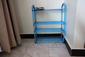 A blue metal shelf unit with three shelves, placed against a wall with a tiled floor. - Simbego Cottages  (Lira)