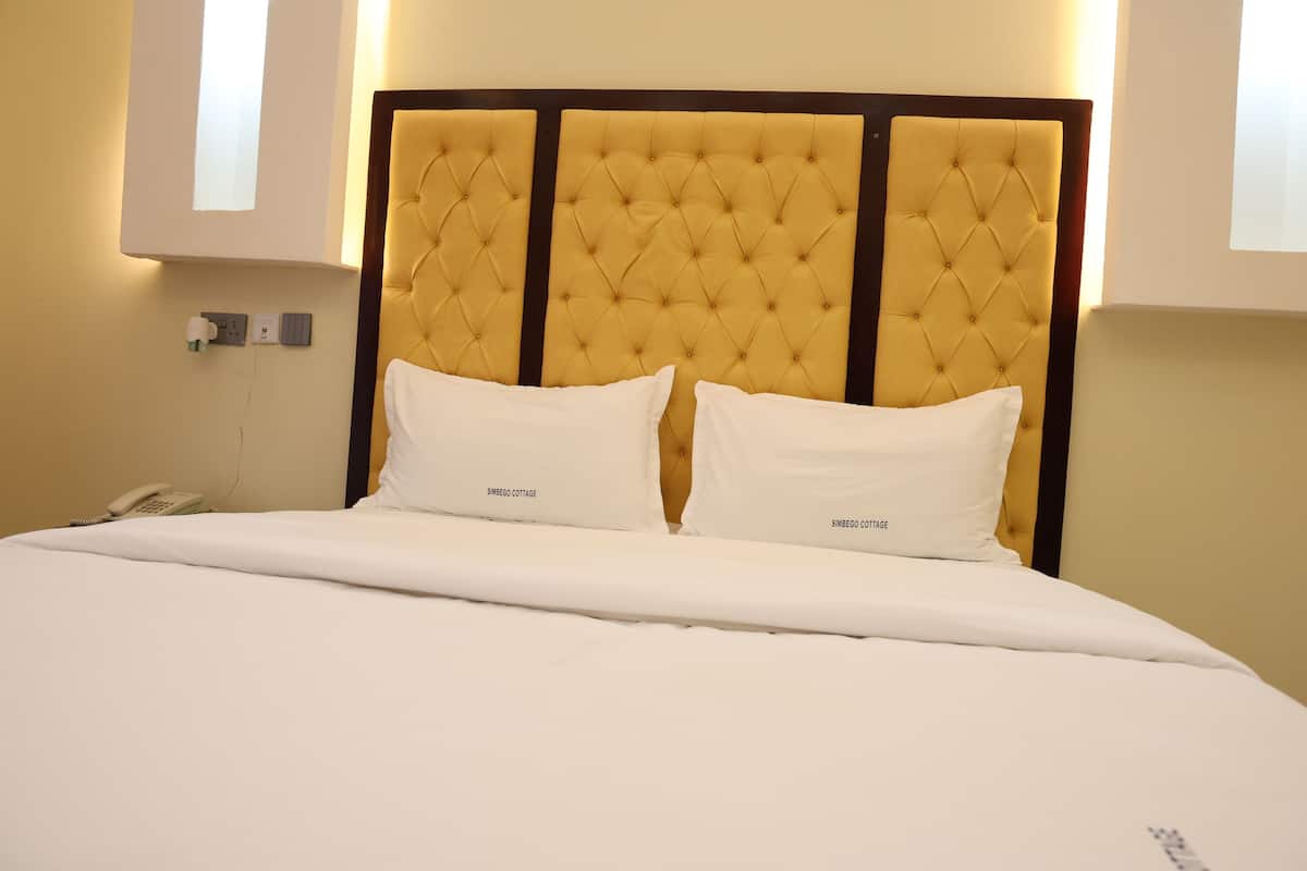 Habitación de hotel con una cama grande, cabecera capitonada y teléfono junto a la cama.