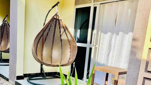 A porch with wicker chairs, a wooden planter with green plants, and a tiled floor. - Simbego Cottages  (Lira)