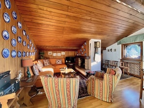 Ein gemütliches Wohnzimmer mit Holzwänden, einem Kamin und einem Fernseher.