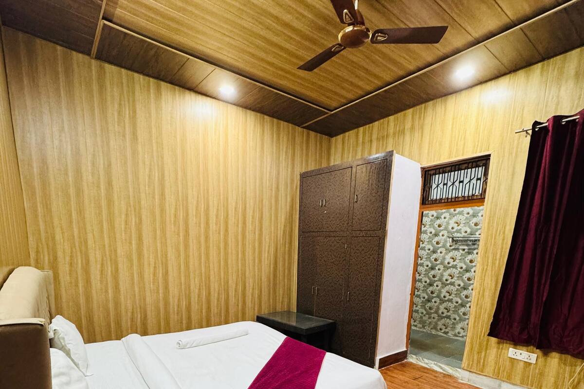 Un dormitorio con cama, armario, ventilador de techo y ventana con cortinas.