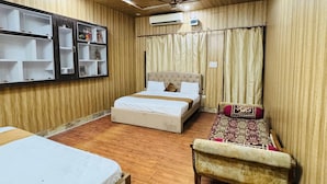 Habitación de hotel con techo de madera, una cama, un sofá y una pequeña mesa.