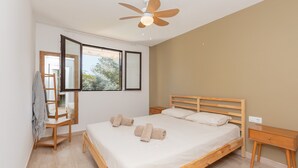Ein Schlafzimmer mit einem hölzernen Bett, einem Deckenventilator, einem Fenster und einem Nachttisch.