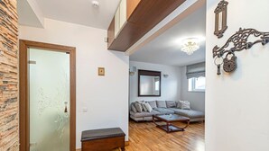 Uma sala de estar com sofá, banqueta e mesa de centro.