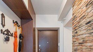 Um corredor com piso de madeira, tapete estampado, porta de madeira e parede com textura.