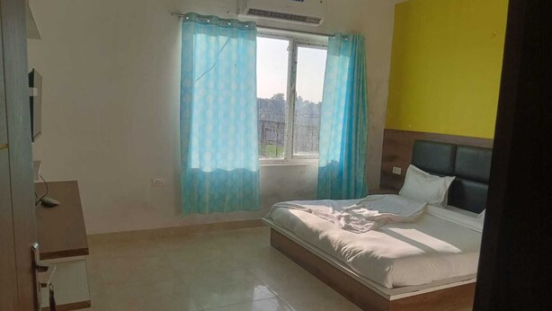Un dormitorio con una cama, una ventana con cortinas, un equipo de aire acondicionado y una pared amarilla.