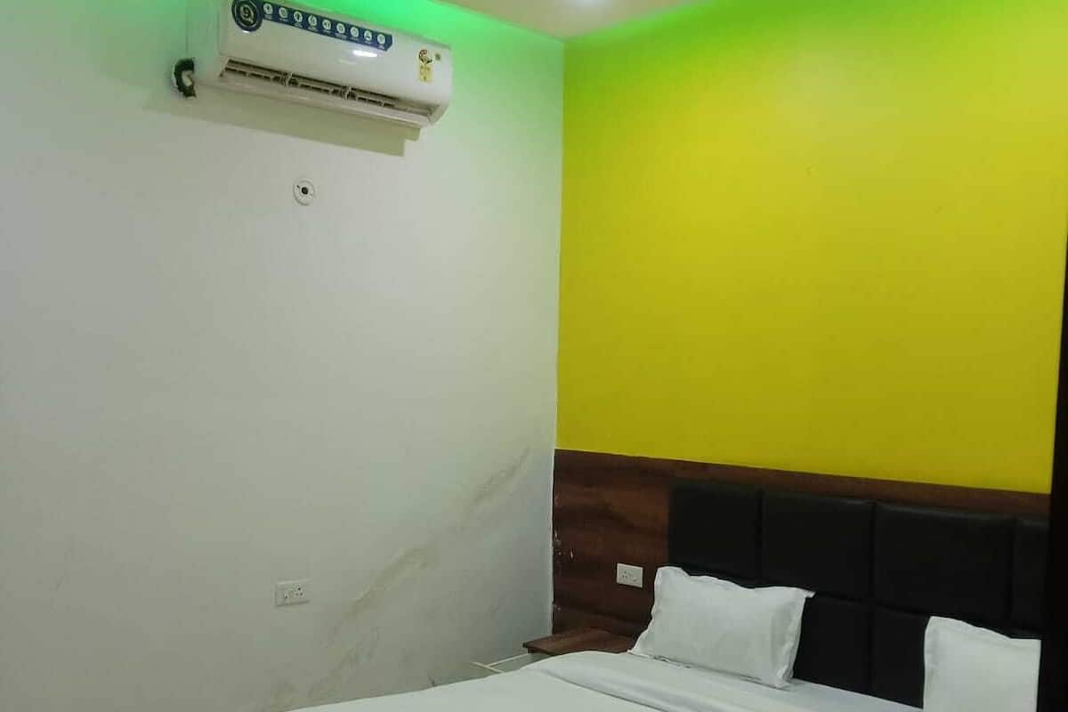 Quarto com cama, ventilador de teto, ar condicionado e parede verde.