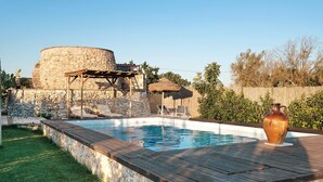 Una piscina amb una paret de pedra, un pont d'obra i una construcció de pedra rústica.