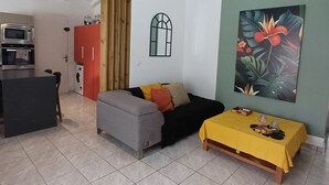 Een ruime woonkamer met een grijze bank, een gele tafel en een rode kast.