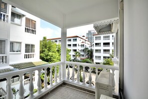 A balcony with white balustrades, a tiled floor, and a view of surrounding buildings and greenery. - Spacious Corner 1-bedroom Condo With 2 Balconies - Baan Suan Lalana (Pattaya)