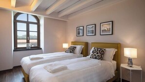 Una habitación de hotel con dos camas, un ventanal grande y tres cuadros enmarcados en la pared.