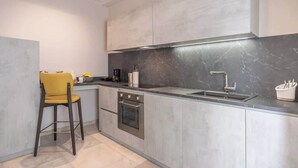 Una cocina moderna con armarios grises, un horno de acero inoxidable y una silla amarilla.