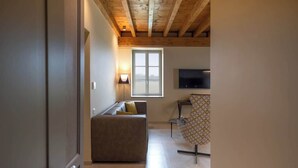Una habitación con sofá, una silla estampada, televisor y ventana con luz natural.