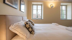 Ein Schlafzimmer mit einem großen Bett, zwei Fenstern und einer Wandleuchte.