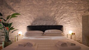 A bed with neatly folded towels, a potted plant, and two bedside lamps. - Villa Diana - Private Villa with pool (Provincia di Brescia)