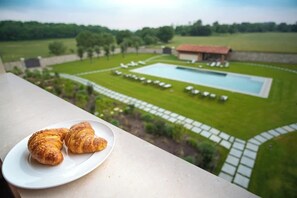A balcony with croissants on a plate, overlooking a swimming pool and a grassy area with lounge chairs. - Borgo di Drugolo Apartment n.14 (Drugolo)
