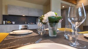 A dining table set with plates, cutlery, and wine glasses, with a vase of flowers and a green plant in the center. - Borgo di Drugolo Apartment n.11 (Drugolo)