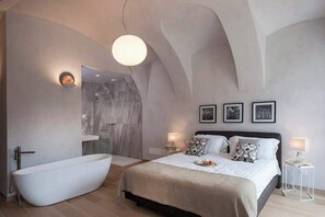 Un dormitorio moderno con una cama grande, una bañera independiente y un diseño minimalista.
