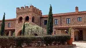 Un bâtiment en pierre doté d’une tour, de fenêtres en arc de cercle et d’une cour pavée.