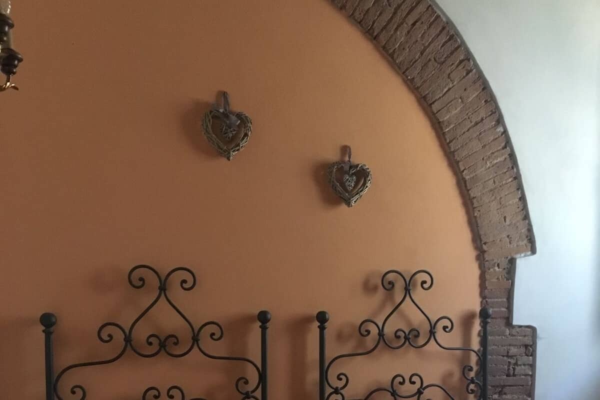 Un dormitorio con dos camas, un arco de ladrillo y apliques decorativos.