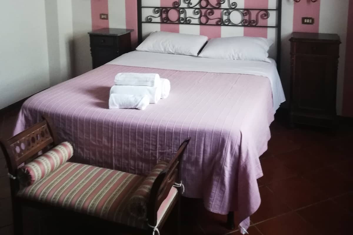 Un dormitorio con una cama, una silla y una mesita de noche.
